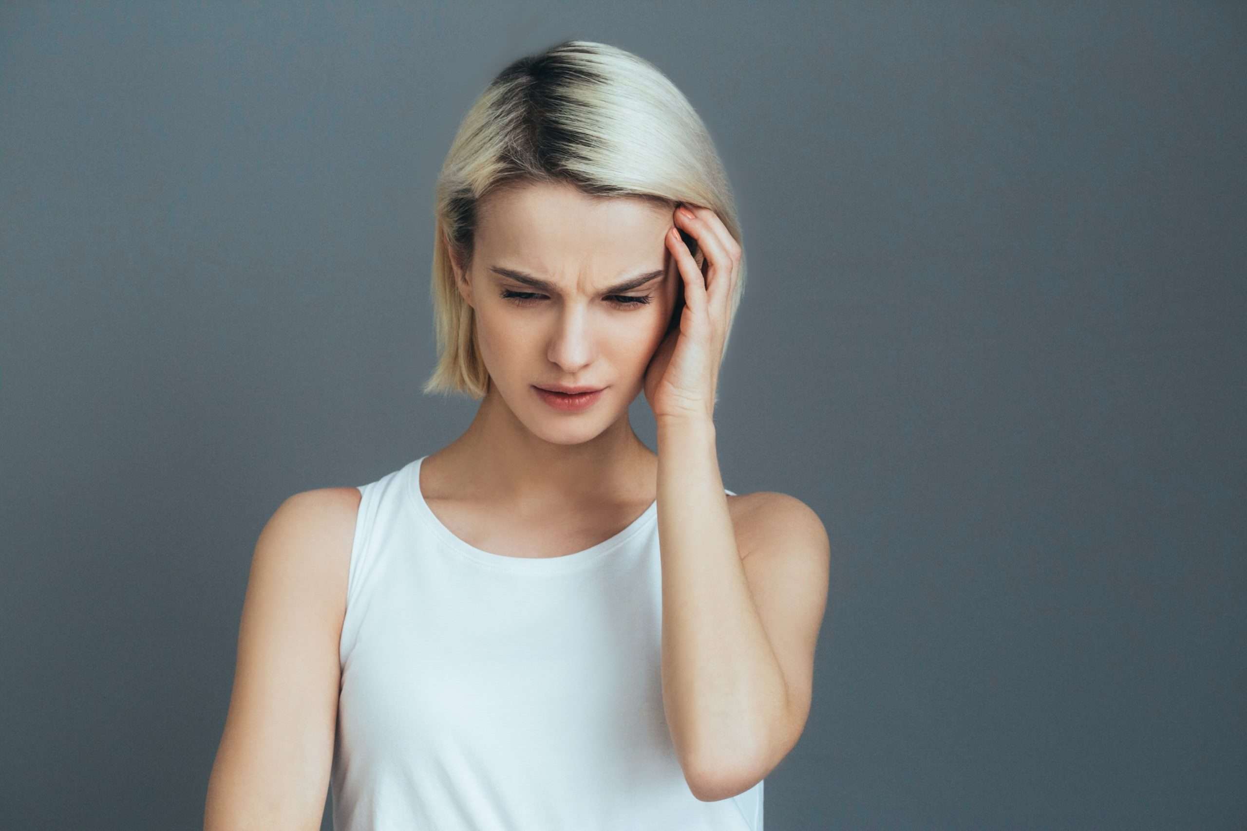 Headache woman portrait. Girl with pain head and neck over gray