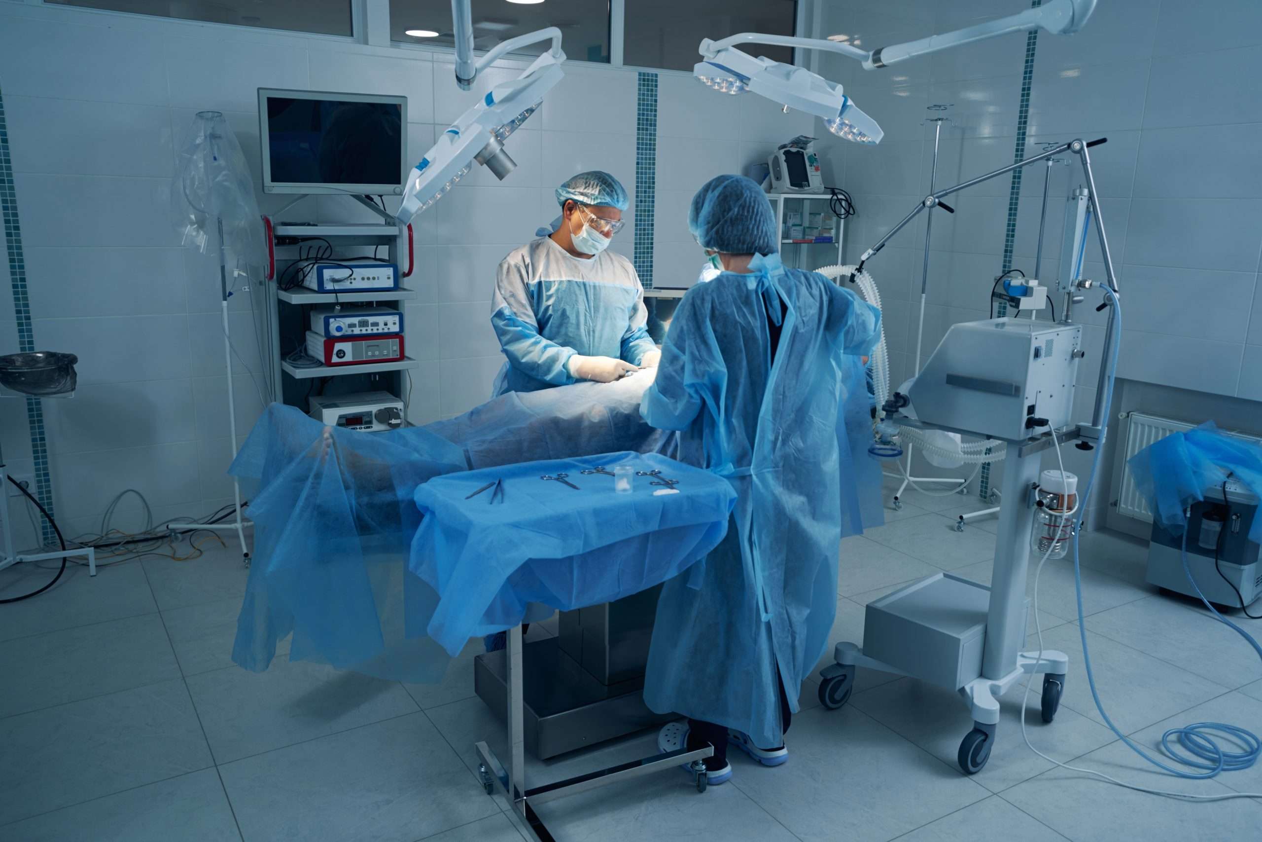 Two surgery experts conducting laparoscopic operation on patient